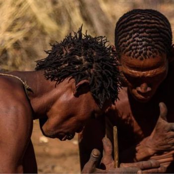 Deux personnes bushman en tenue traditionnelle faisant du feu dans la région du Bushmanland
