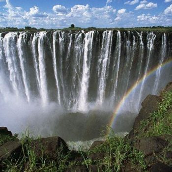 A rainbow forms as the turbulent waters of Zambezi River rush over Victoria Falls. Zimbabwe. ca. 1970-1995 Zimbabwe